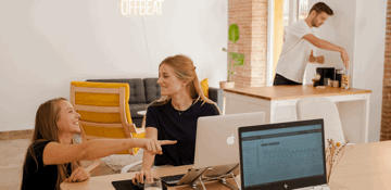 Het Offbeat-team aan het werk op kantoor, met het Offbeat-neonbord aan de muur